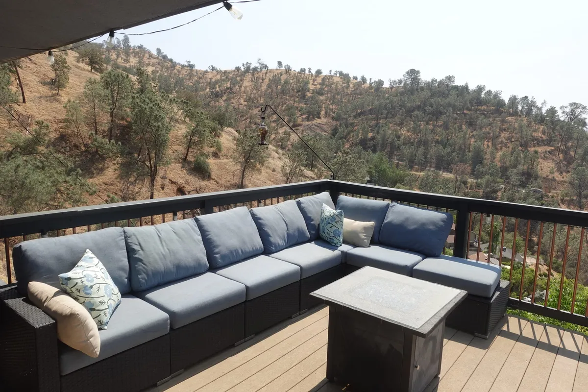 A covered deck with seating and a fire table at our residence above Millerton Lake
